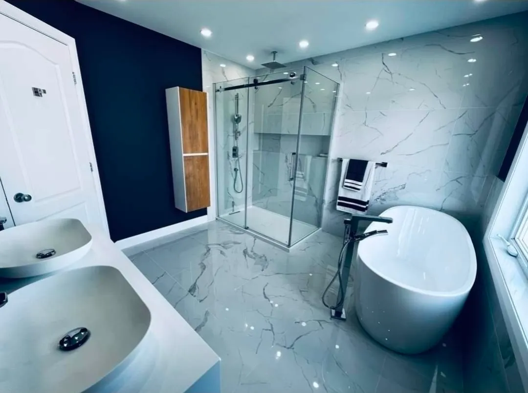 Salle de bain terminée avec douche vitrée, baignoire autoportante et surfaces au fini marbré